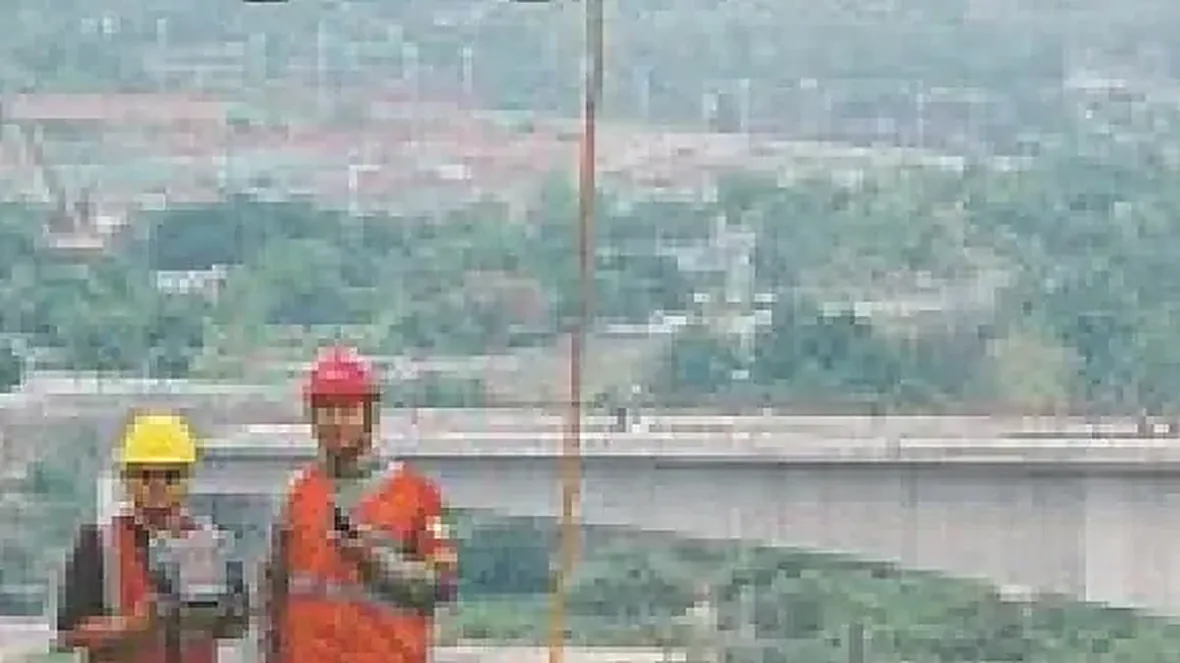 Operación de izado de carga con Matrice 400, cable colgando de la aeronave con dos operarios en tierra preparados para recibirlo