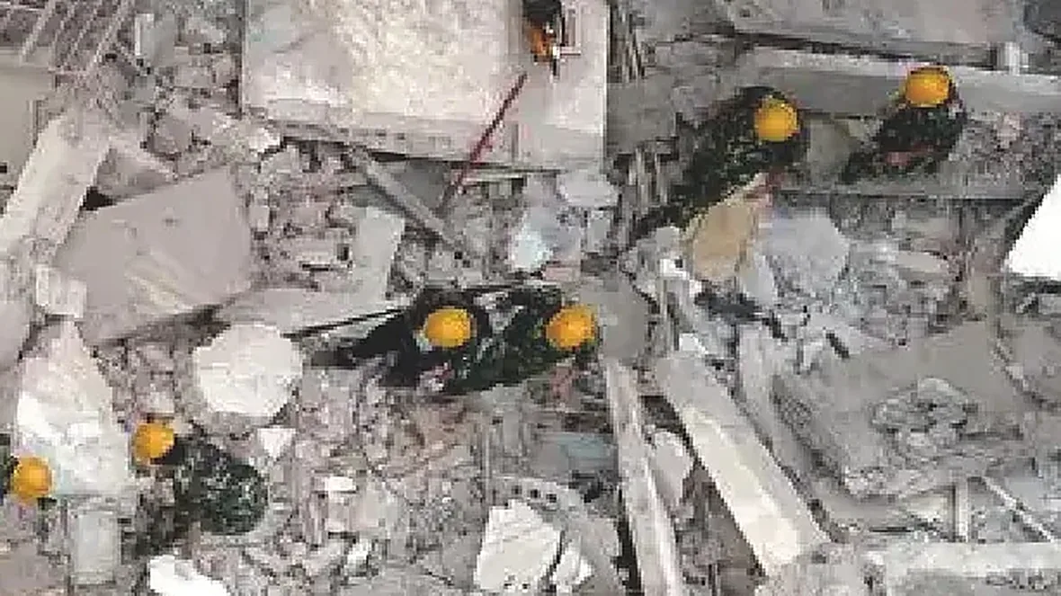 Edificio derrumbado tras un terremoto, rescatistas buscando entre los escombros, acceso terrestre bloqueado y suministros que requieren entrega aérea